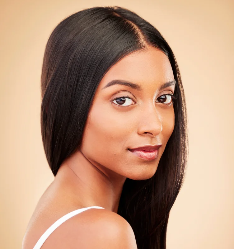 Leicht lächelnde, brünette Frau mit langem offenem Haar von der Seite mit Blick zur Kamera