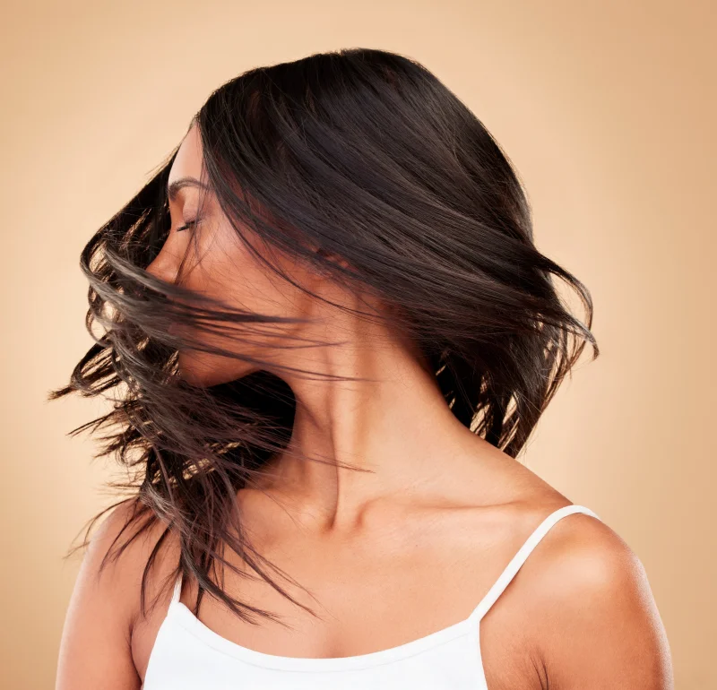 Brünette Frau schüttelt ihren Kopf seitliche und ihr Haare legen sich in einem Wirbel um ihren Kopf